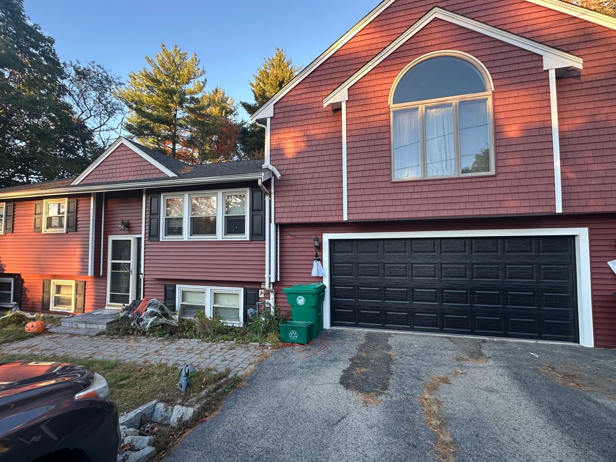 Black raised-panel garage door on red colonial home with arched window in Massachusetts