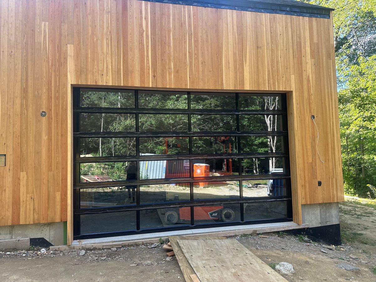 Modern full-view aluminum and glass garage door on contemporary cedar building in Massachusetts